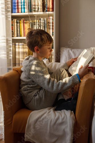 A boy sitting in an armchair and reading a book