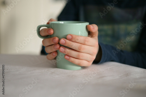 A young boy (child) holding a cup with both hands