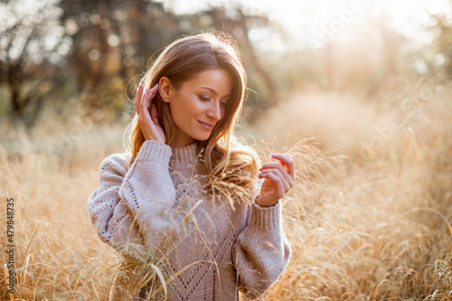 Happy young woman outdoors at autumn sunset. girl in a field of dry grass   