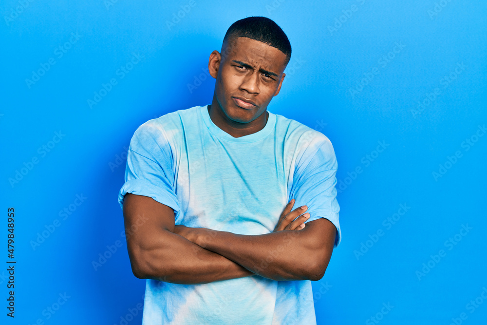Young black man wearing tye die t shirt skeptic and nervous, disapproving expression on face with crossed arms. negative person. Young black man wearing tye die t shirt skeptic and nervous, disapproving expression on face with crossed arms. negative person.