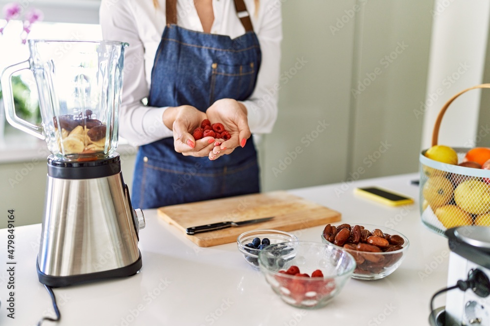 Young blonde woman holding raspberries at kitchen Young blonde woman holding raspberries at kitchen