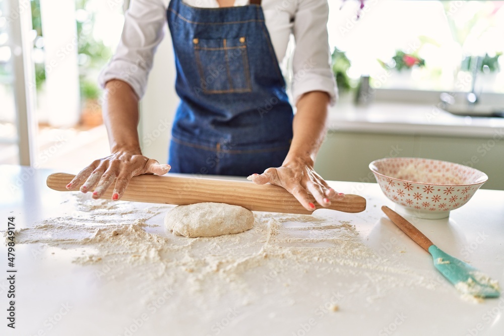 Young blonde woman kneading pizza dough at kitchen