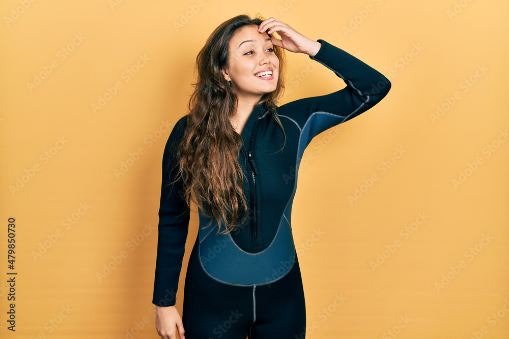 Young hispanic girl wearing diver neoprene uniform smiling confident touching hair with hand up gesture, posing attractive and fashionable Young hispanic girl wearing diver neoprene uniform smiling confident touching hair with hand up gesture, posing attractive and fashionable
