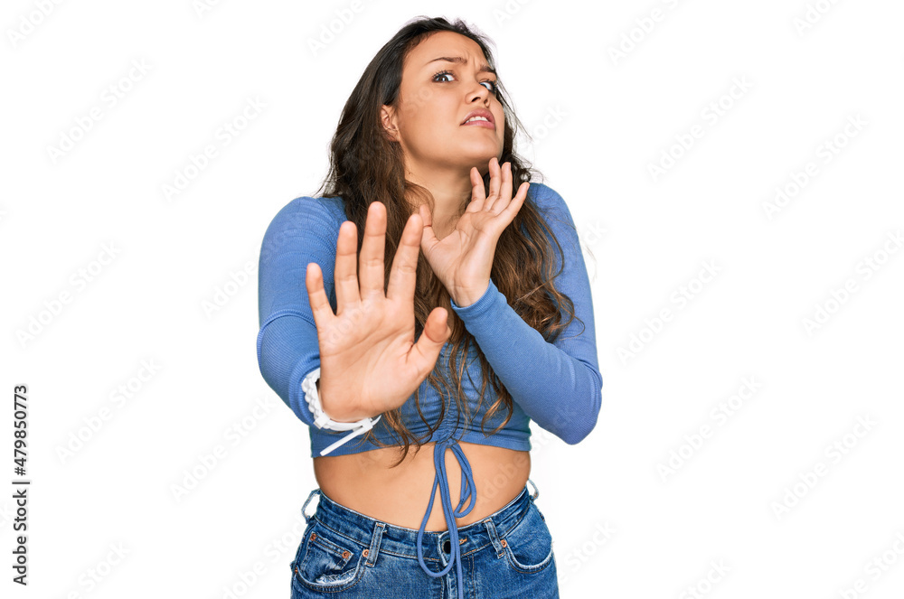 Young hispanic girl wearing casual clothes afraid and terrified with fear expression stop gesture with hands, shouting in shock. panic concept. Young hispanic girl wearing casual clothes afraid and terrified with fear expression stop gesture with hands, shouting in shock. panic concept.