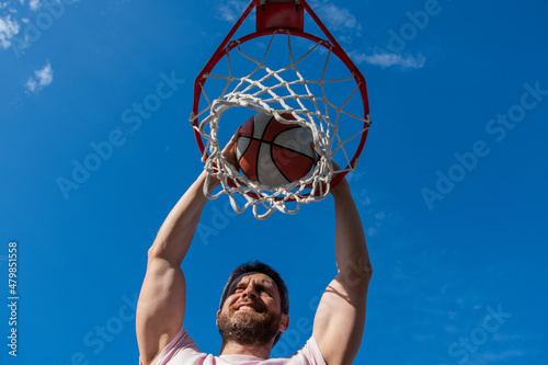 dunk in basket. slam dunk in motion. summer activity. smiling man with basketball ball