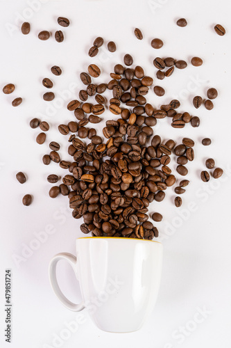 coffee beans come out of a cup in front of a white background