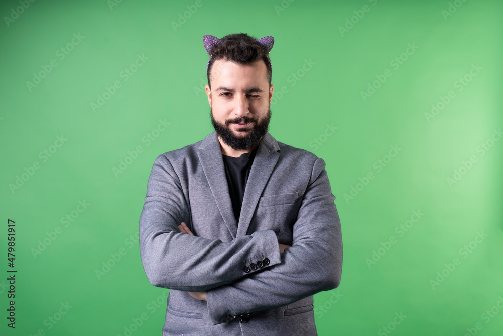 Man in suit with kitten headband winks at camera with crossed arms