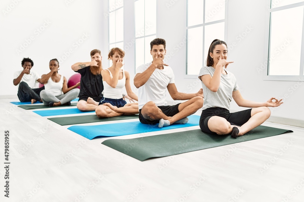 Group of young people smiling happy training yoga nadi shodhana breath at sport center. Group of young people smiling happy training yoga nadi shodhana breath at sport center.