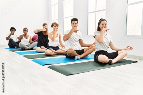 Group of young people smiling happy training yoga nadi shodhana breath at sport center.