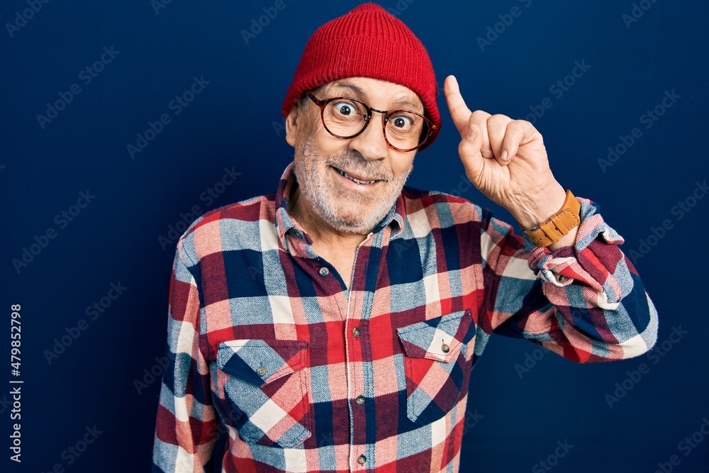Naklejka premium Handsome mature man wearing hipster look with wool cap pointing finger up with successful idea. exited and happy. number one.