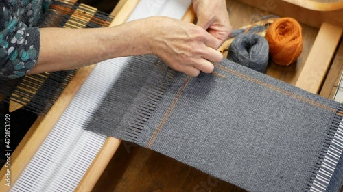 Artisan finishing the weaving project to stop it from unraveling. Stitching work on the end of the woven gray fabric photo