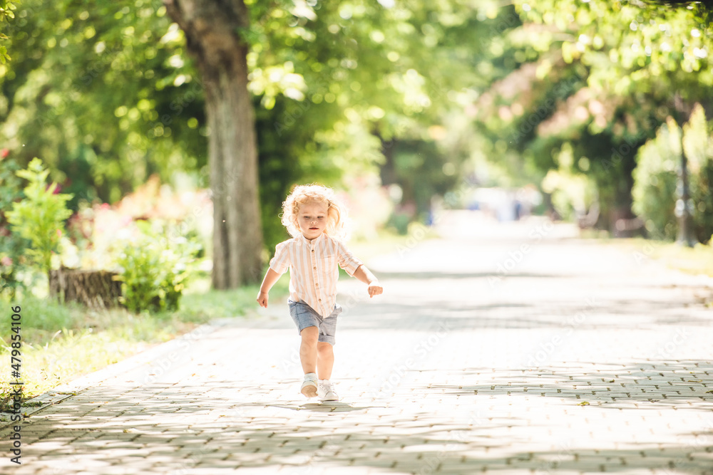 Cute little boy with curly blonde hair playing in park Cute little boy with curly blonde hair playing in park