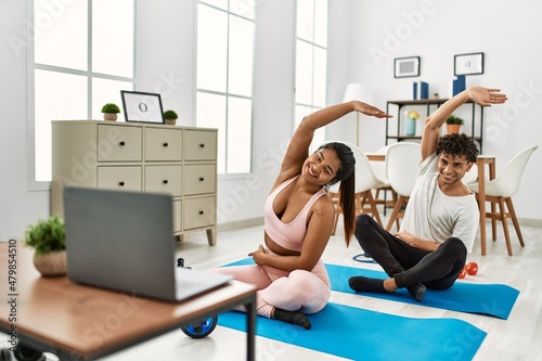 Young latin sporty couple smiling happy having online sport class at home.