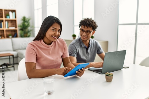 Young latin couple working using laptop and touchpad sitting on the table at home. © Krakenimages.com