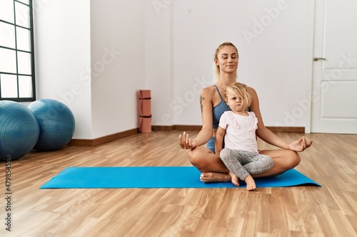 Mother and daughter smiling confident training yoga at sport center