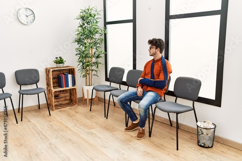 Young hispanic man injuried sitting on chair at clinic waiting room