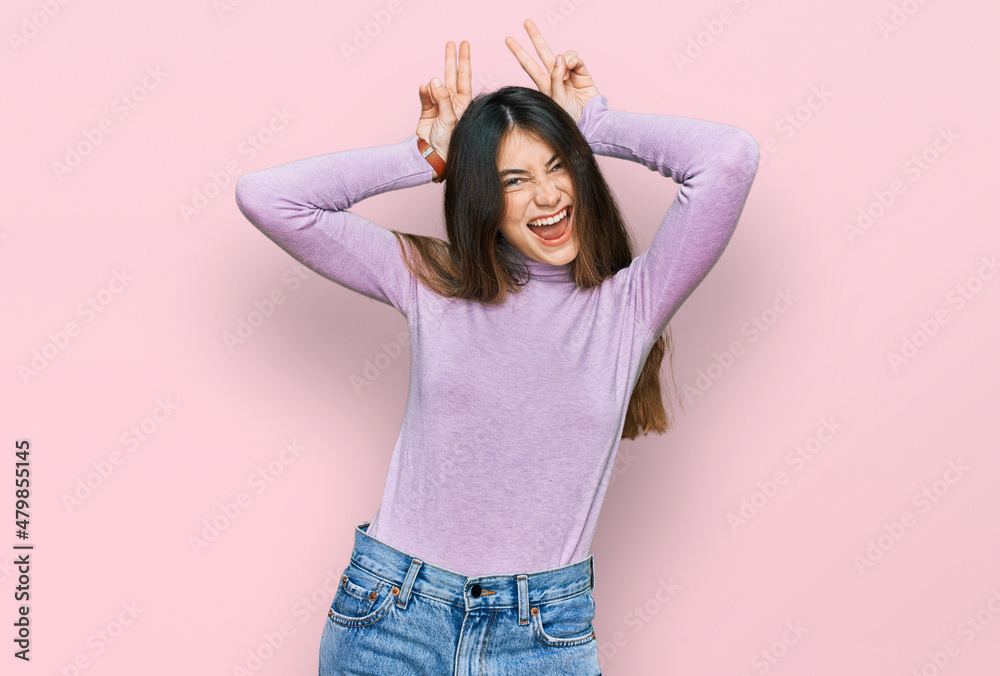 Young beautiful teen girl wearing turtleneck sweater posing funny and crazy with fingers on head as bunny ears, smiling cheerful Young beautiful teen girl wearing turtleneck sweater posing funny and crazy with fingers on head as bunny ears, smiling cheerful