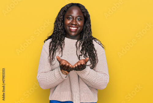Young african woman wearing wool winter sweater smiling with hands palms together receiving or giving gesture. hold and protection