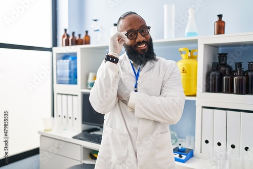 Young african american man wearing scientist uniform standing at laboratory