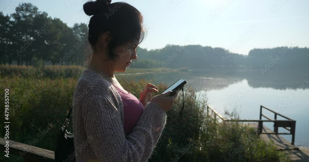 Young Pretty Woman Use Smartphone Tapping Touchscreen Texting Resting Relaxing on Beautiful Nature in City Park. Summer Morning Sunny Day 4K Young Pretty Woman Use Smartphone Tapping Touchscreen Texting Resting Relaxing on Beautiful Nature in City Park. Summer Morning Sunny Day 4K