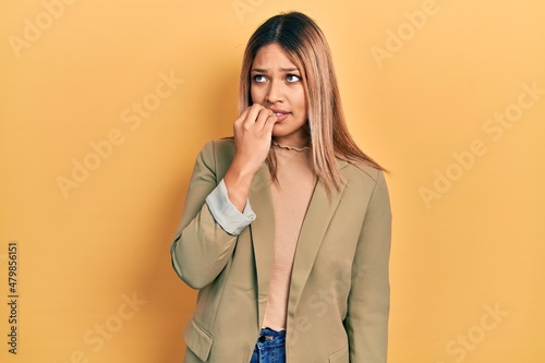 Beautiful hispanic woman wearing business jacket looking stressed and nervous with hands on mouth biting nails. anxiety problem.