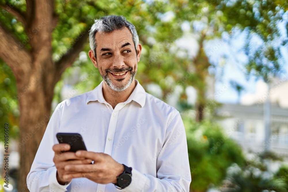 Middle age grey-haired man smiling happy using smartphone at the city. Middle age grey-haired man smiling happy using smartphone at the city.