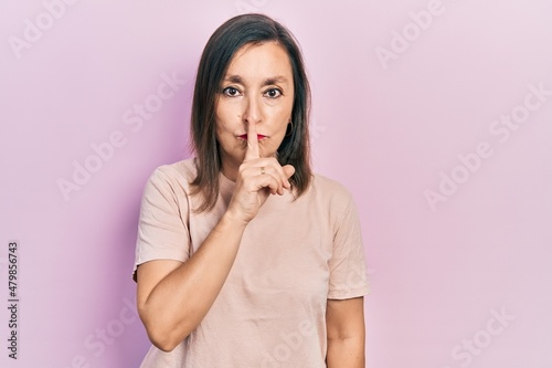 Middle age hispanic woman wearing casual clothes asking to be quiet with finger on lips. silence and secret concept.