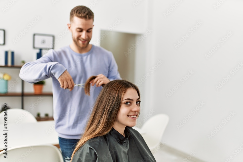 Fototapeta premium Young man cutting hair his girlfriend at home.