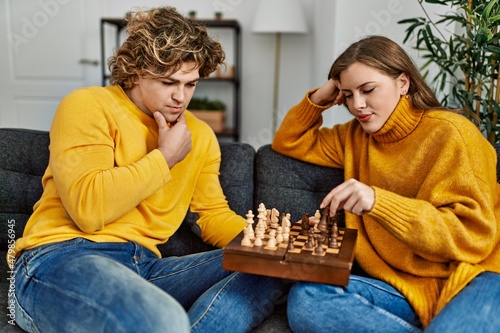 Young caucasian couple concentrate playing chess at home