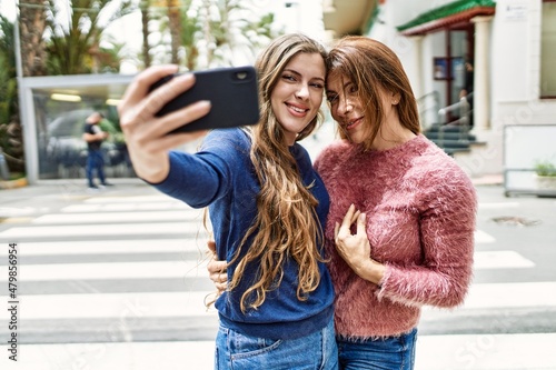 Mother and daughter hugging each other and making selfie by the smartphone at street © Krakenimages.com