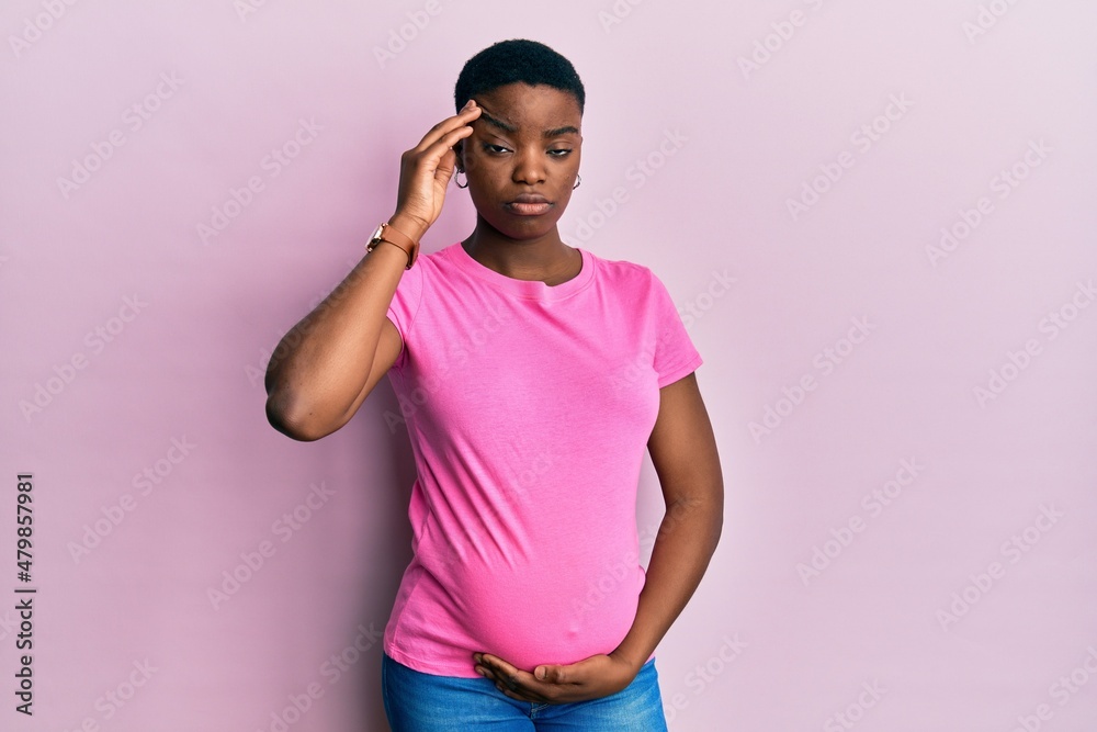 Young african american woman expecting a baby, touching pregnant belly worried and stressed about a problem with hand on forehead, nervous and anxious for crisis Young african american woman expecting a baby, touching pregnant belly worried and stressed about a problem with hand on forehead, nervous and anxious for crisis