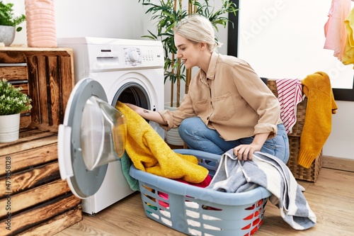 Young caucasian woman smiling confident washing clothes at laundry room