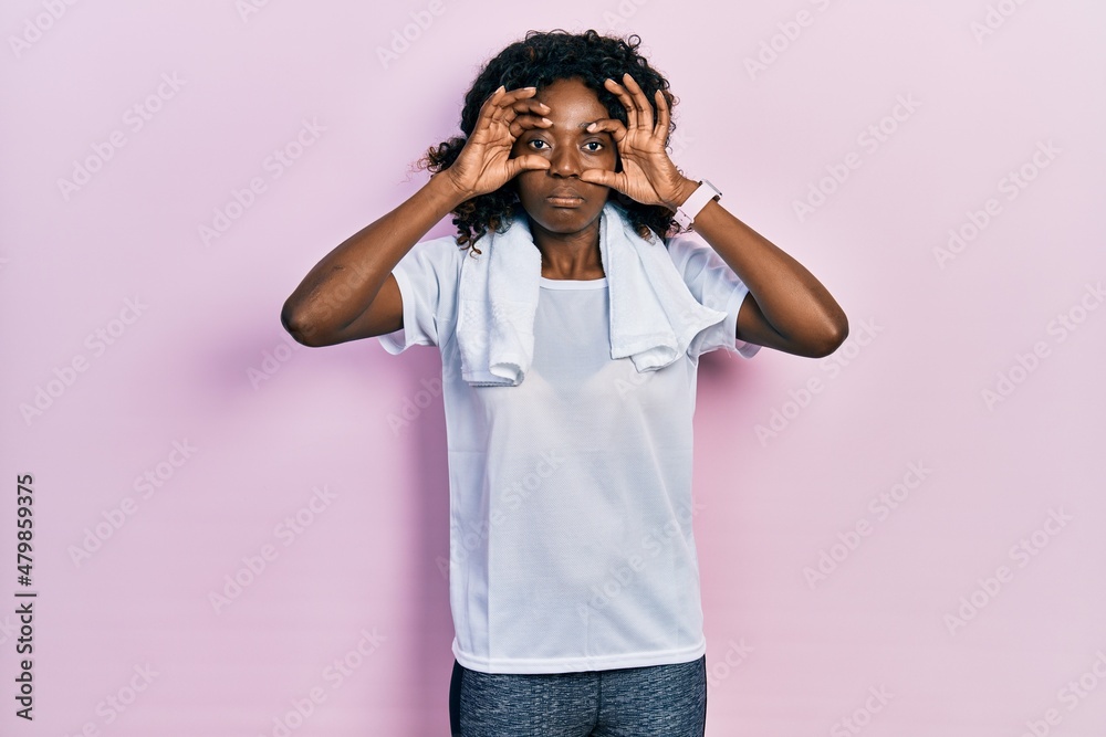 Young african american woman wearing sportswear and towel trying to open eyes with fingers, sleepy and tired for morning fatigue Young african american woman wearing sportswear and towel trying to open eyes with fingers, sleepy and tired for morning fatigue