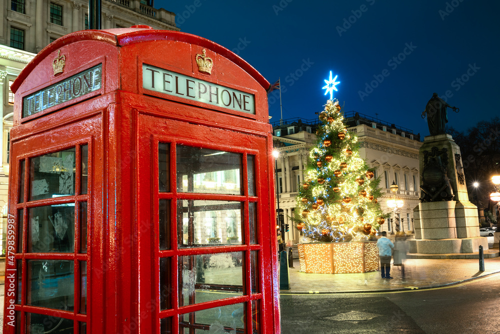 Christmas time in London: a red telephone booth in front of an illuminated Christmas Tree in Central London, UK, during night time Christmas time in London: a red telephone booth in front of an illuminated Christmas Tree in Central London, UK, during night time