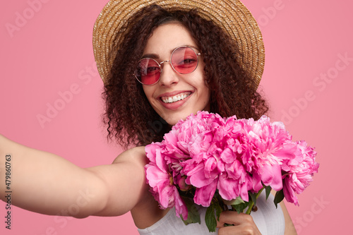 Happy woman taking selfie with pink flowers