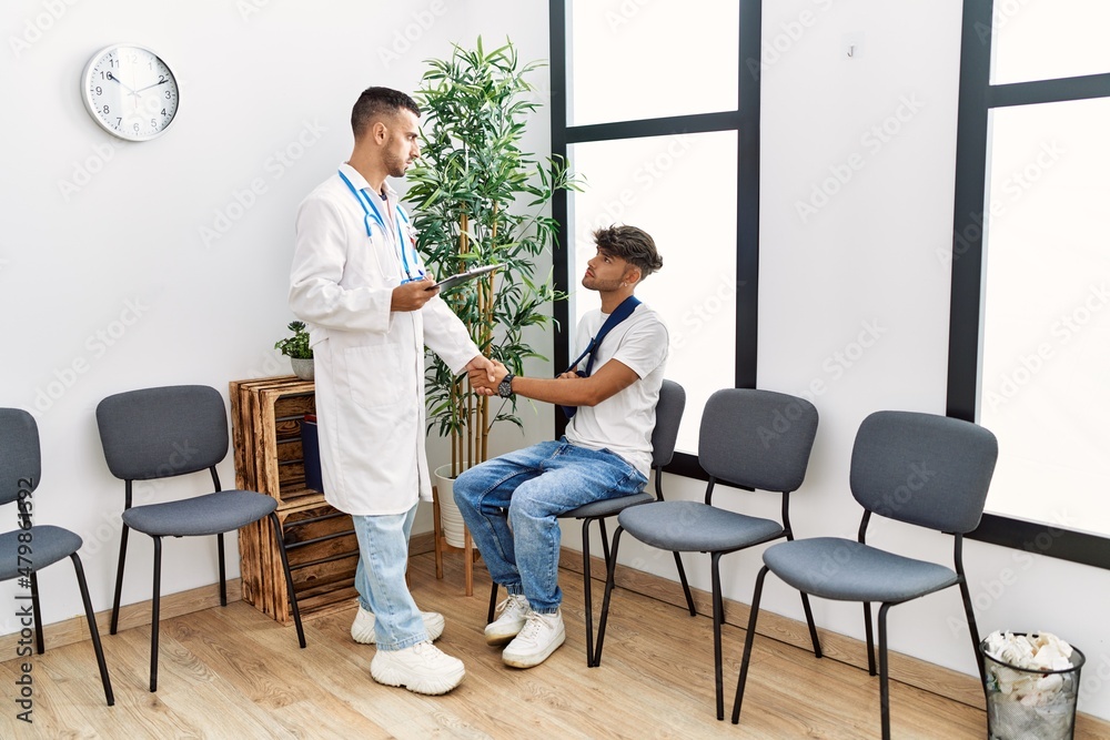 Two hispanic men doctor and patient shake hands at hospital waiting room Two hispanic men doctor and patient shake hands at hospital waiting room