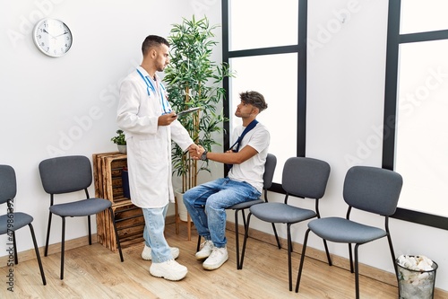Two hispanic men doctor and patient shake hands at hospital waiting room © Krakenimages.com