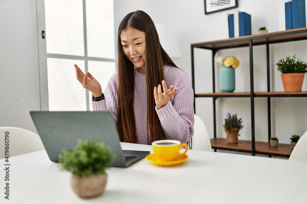 Young chinese girl having video call using laptop sitting on the table at home. Young chinese girl having video call using laptop sitting on the table at home.