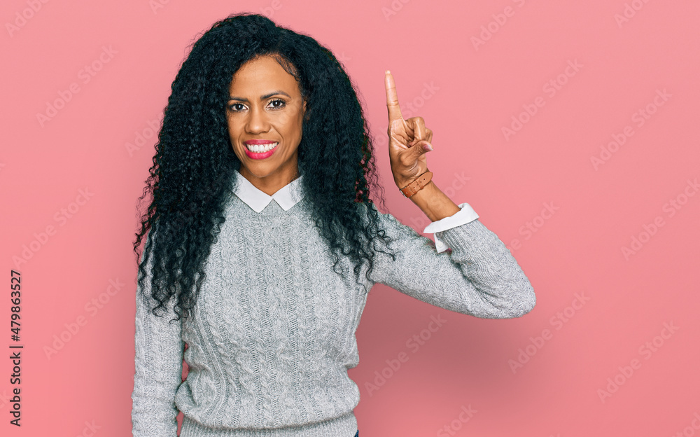 Middle age african american woman wearing casual clothes pointing finger up with successful idea. exited and happy. number one. Middle age african american woman wearing casual clothes pointing finger up with successful idea. exited and happy. number one.