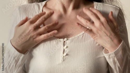 Woman in white shirt practicing EFT or emotional freedom technique - tapping on the collarbone point photo