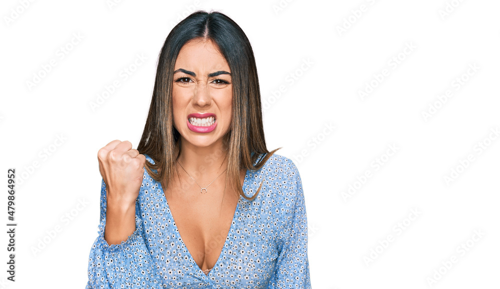 Young hispanic woman wearing casual clothes angry and mad raising fist frustrated and furious while shouting with anger. rage and aggressive concept. Young hispanic woman wearing casual clothes angry and mad raising fist frustrated and furious while shouting with anger. rage and aggressive concept.