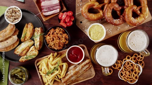 Putting plate with smoked sasuages and fried potatoes top view, pickled cucumbers, bratwursts and fresh pretzels on table. Traditional German Cuisine. Composition of Cooked National Czech Food.  photo