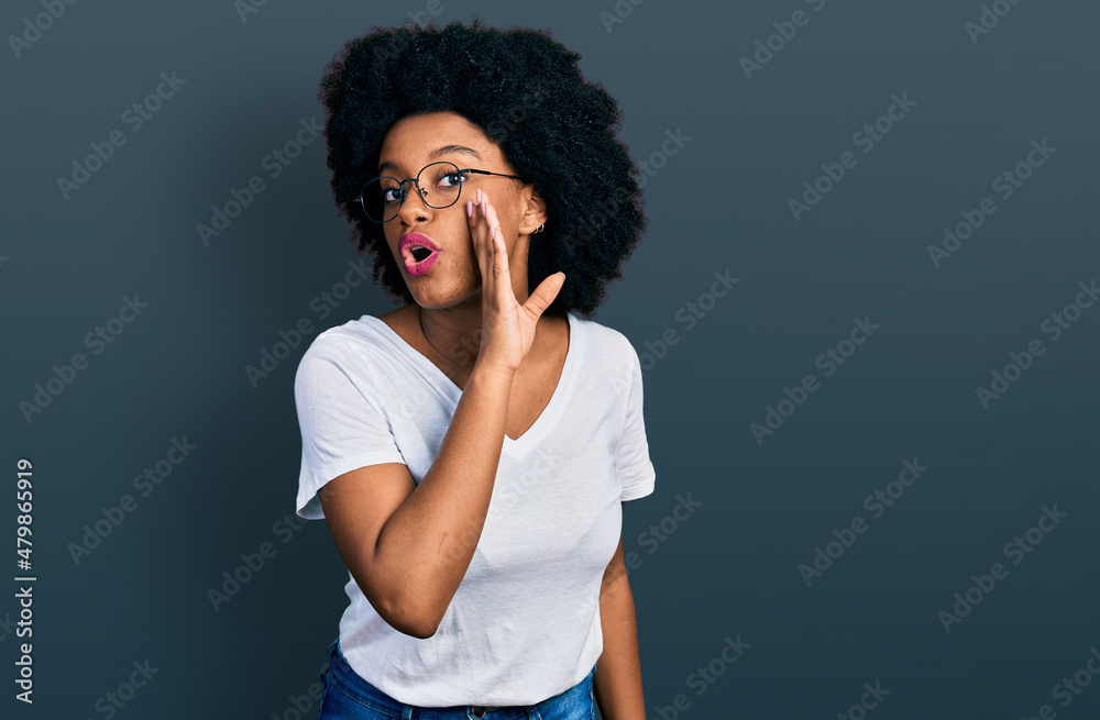 Young african american woman wearing casual white t shirt hand on mouth telling secret rumor, whispering malicious talk conversation Young african american woman wearing casual white t shirt hand on mouth telling secret rumor, whispering malicious talk conversation