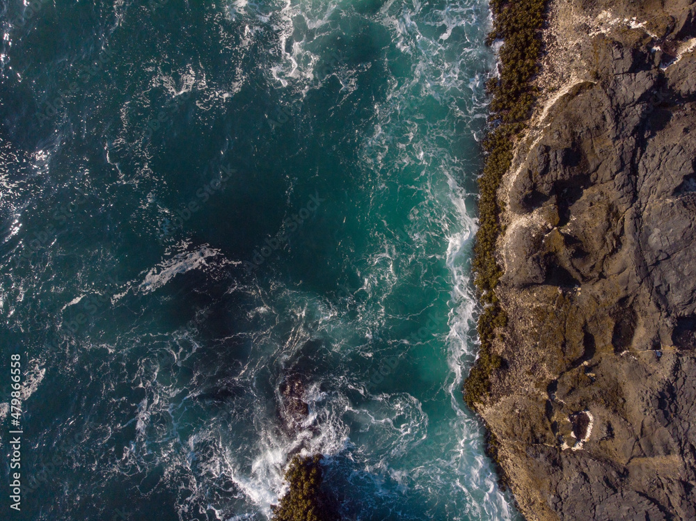 Obraz premium Aerial photograph. Seething ocean water. Foam waves crash against the rocky shore. Beautiful nature. Ecology, geology. Color image. There are no people in the photo. Minimalism. Abstraction.