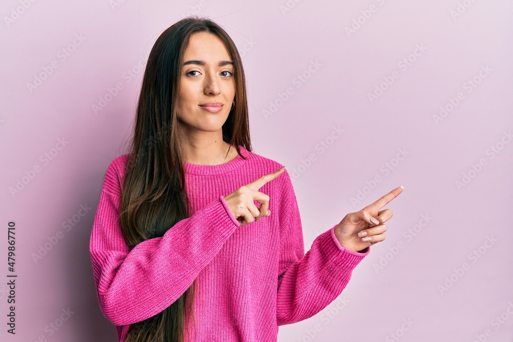 Young hispanic girl pointing with fingers to the side relaxed with serious expression on face. simple and natural looking at the camera. Young hispanic girl pointing with fingers to the side relaxed with serious expression on face. simple and natural looking at the camera.