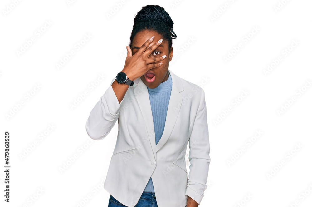 Young african american woman wearing business clothes peeking in shock covering face and eyes with hand, looking through fingers with embarrassed expression. Young african american woman wearing business clothes peeking in shock covering face and eyes with hand, looking through fingers with embarrassed expression.