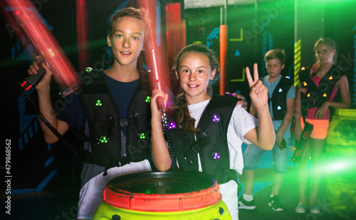 Cheerful teen girl and boy with laser pistols posing together in laser tag labyrinth.. © JackF
