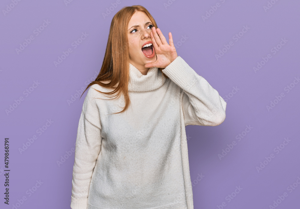 Young irish woman wearing casual winter sweater shouting and screaming loud to side with hand on mouth. communication concept. Young irish woman wearing casual winter sweater shouting and screaming loud to side with hand on mouth. communication concept.