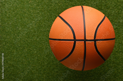 Orange basketball ball on a green sports field. Close-up. Minimalism. There is a place to insert. Sports, outdoor activities, healthy lifestyle. photo