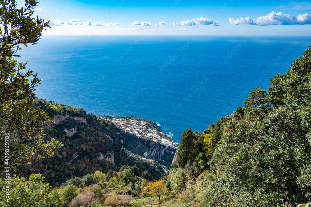 The Italian village of Praiano, seen from above, from the Path of the Gods (Sentiero degli Dei) along the scenic Amalfi Coast of Italy, with the blue Tyrrhenian Sea and blue sky and clouds